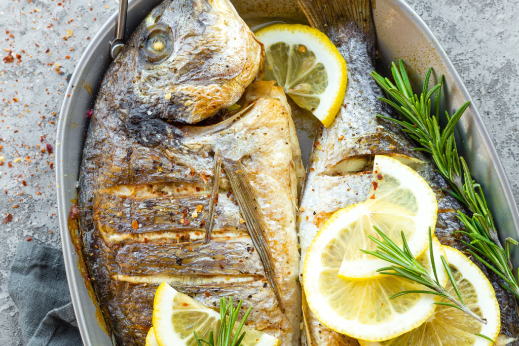 Whole baked fish served with fresh lemon slices and herbs for a healthy, high-protein meal.