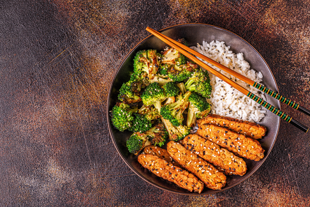A healthy meal featuring grilled tempeh, steamed broccoli and rice served in a bowl.