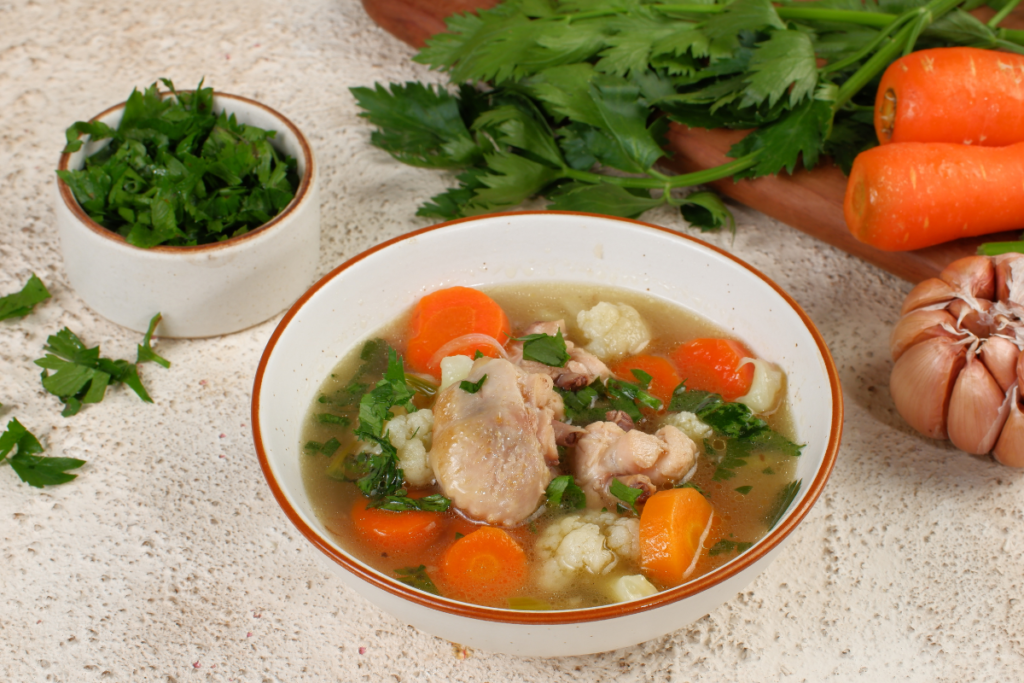 Healthy chicken vegetable soup with carrots, cauliflower, fresh herbs and tender chicken in a light, nutritious broth.