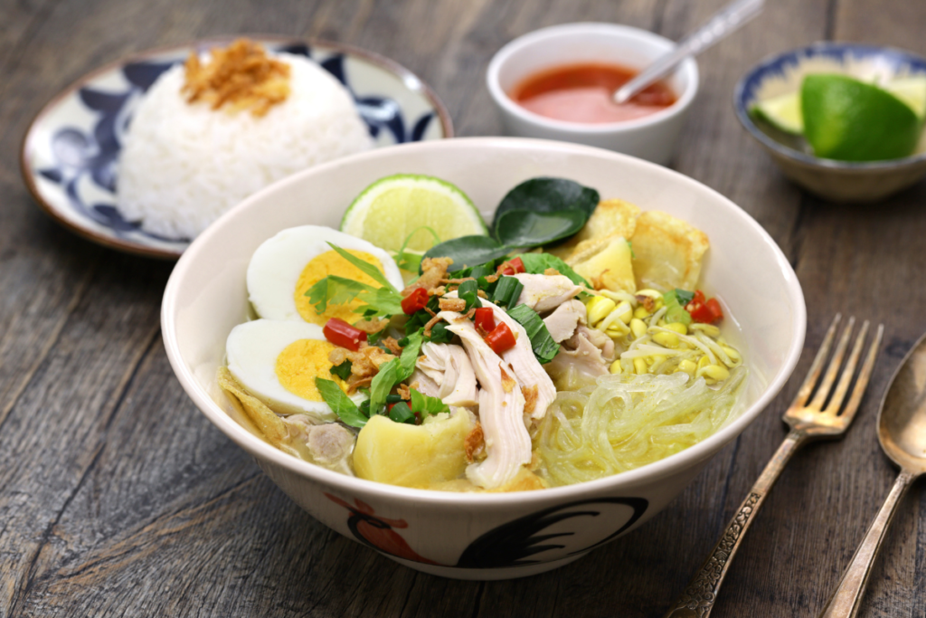 A healthier Chicken Soto served with shredded chicken, glass noodles, boiled egg, bean sprouts and fresh herbs in a light turmeric broth.