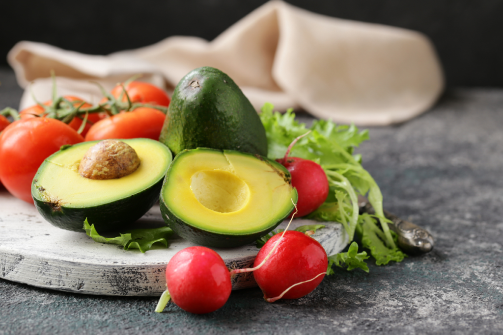 Fresh avocado with tomatoes, radishes and leafy greens on a healthy meal platter
