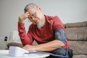 Elderly man feeling unwell while checking his blood pressure at home