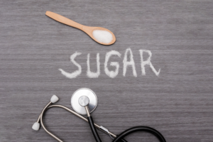 Sugar in a spoon beside a stethoscope representing the health effects of excess sugar intake