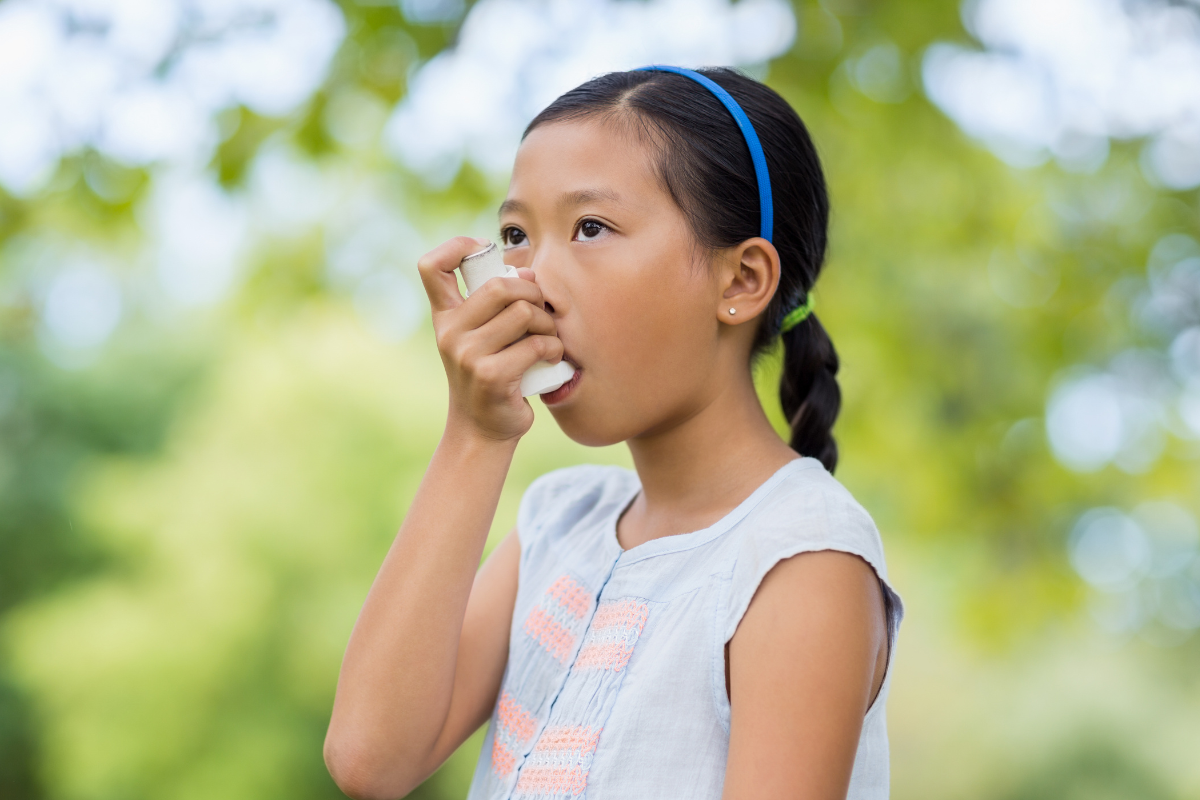 Young child using an asthma inhaler with adult supervision