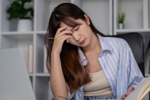 Woman at a desk feeling exhausted and overwhelmed while working