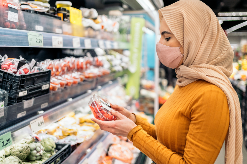 Woman reading a packaged food label while shopping at a supermarket