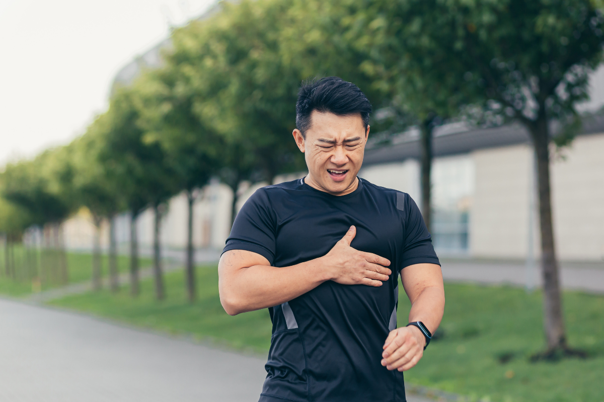 Man experiencing chest pain while exercising outdoors, representing a possible heart attack warning sign