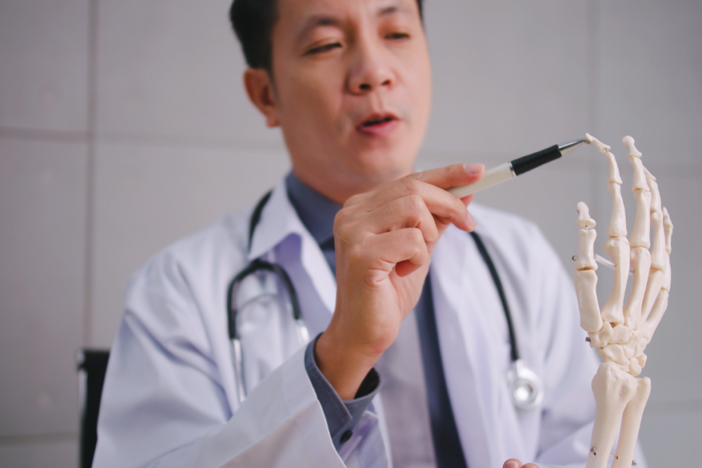 Doctor using a hand skeleton model to explain osteoporosis and bone health