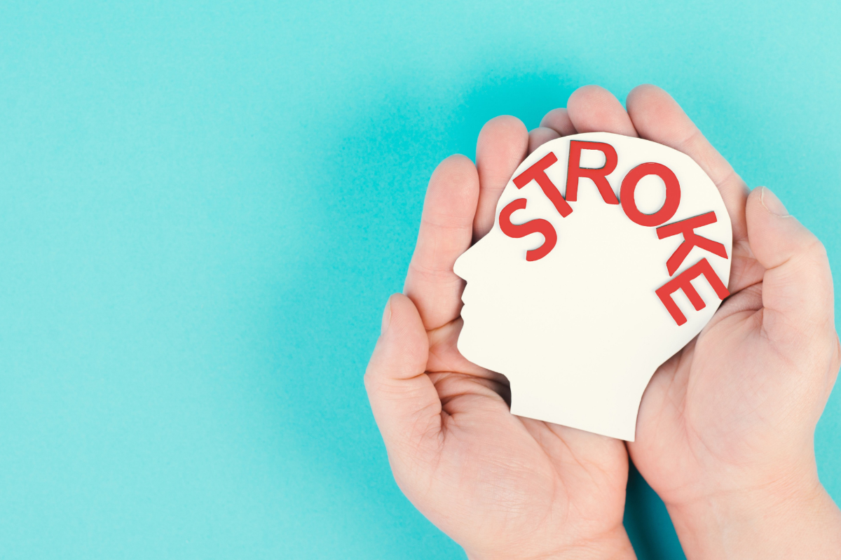 Hands holding a head-shaped cutout with the word stroke, representing stroke awareness and warning signs