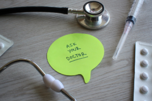 Stethoscope and medical supplies beside a note encouraging people to ask their doctor about their health.
