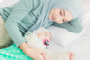 Mother resting beside her sleeping baby during a peaceful sleep routine.