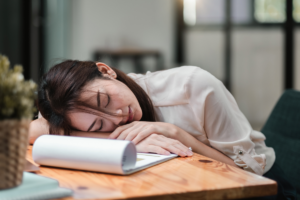 Tired woman resting her head on a desk due to fatigue and low energy