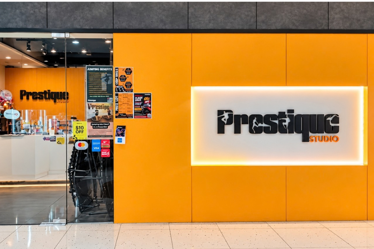 Entrance to Prestique Studio at Marina Square with orange wall and illuminated logo